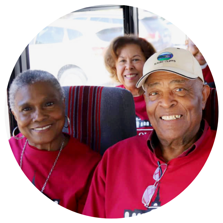 A group of older people from a local Baptist church in Arlington, TX, smiling on a bus.