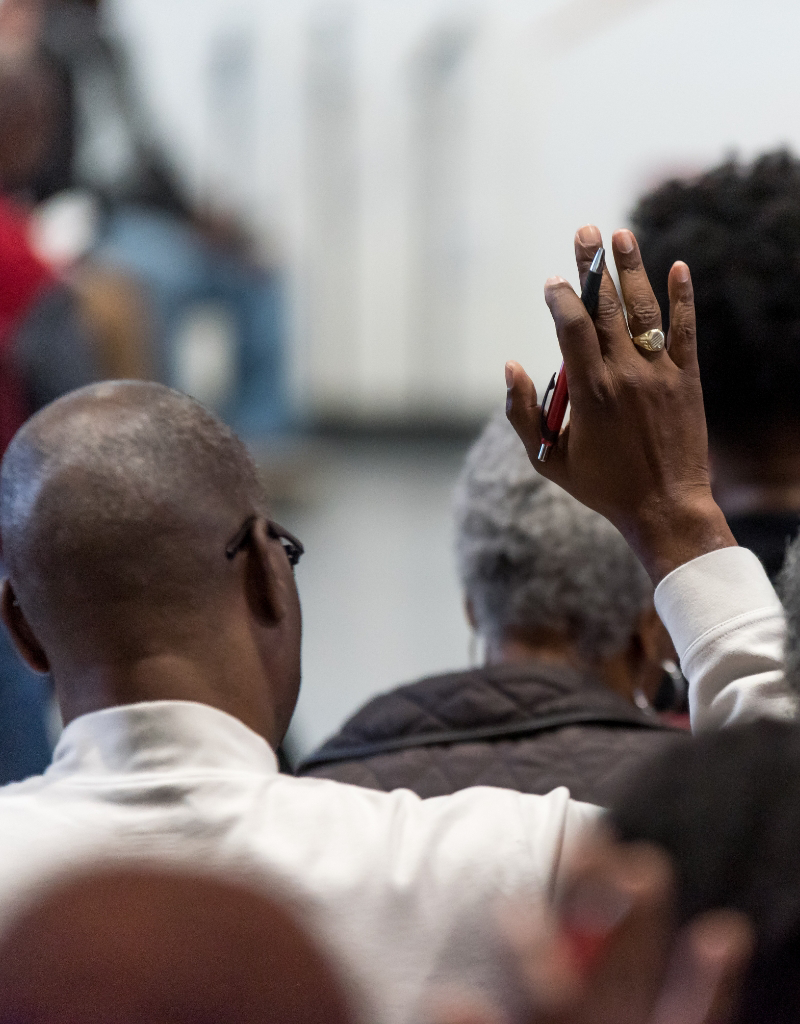 A group of people in a Baptist church with their hands raised.