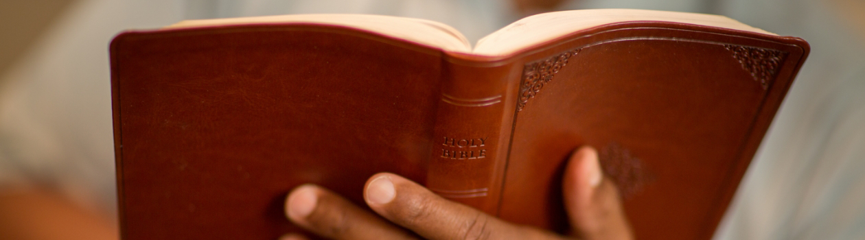 A man is holding a brown Bible in her hands at Mount Olive Baptist Church in Arlington, TX.